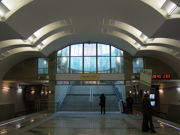 DSC06196.JPG (1.61 МБ) 3603 просмотра Действующий западный вестибюль. Выход к парковке. Даже любопытствующих почти нет. На указателе "выход в город" нет ни одного объекта, к которому можно выйти! (как и на "Битцевском Парке"; кажется это впервые в истории ММ). Впрочем, на поверхности объектов тоже нет, кроме 17й больницы, которая всё равно ближе к восточному вестибюлю. Зато есть освещение естественным светом, просвечивающим насквозь витраж с тоненькими силуэтами деревьев.